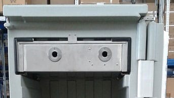 Coffre-fort industriel à deux serrures devant étagères boxées.