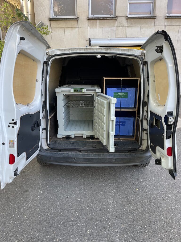 Les portes ouvertes d’une camionnette révèlent des réfrigérateurs médicaux, des conteneurs isothermes prêts à être livrés.